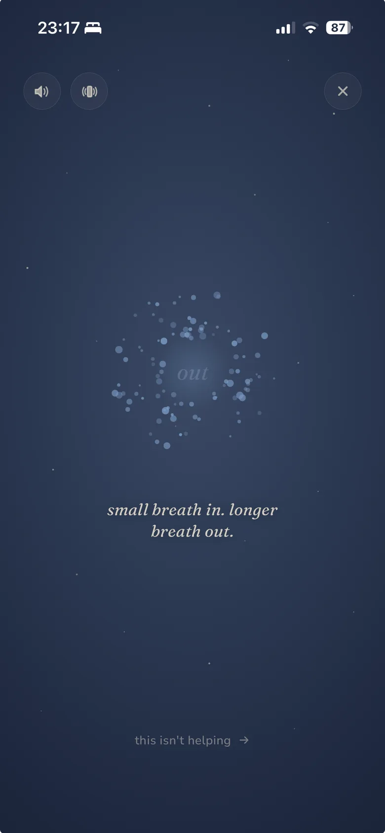 Stillee's breathing screen on iPhone, a dusk-blue dust-particle orb suspended on the exhale, with the caption 'small breath in. longer breath out.' and a quiet 'this isn't helping' escape link at the bottom.